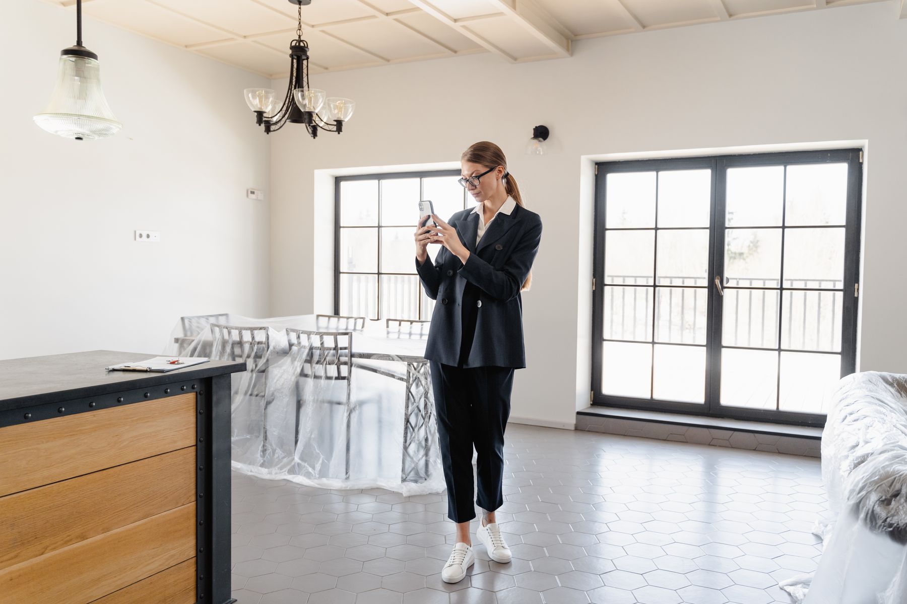Real estate professional photographing the interior of a bright property with a smartphone