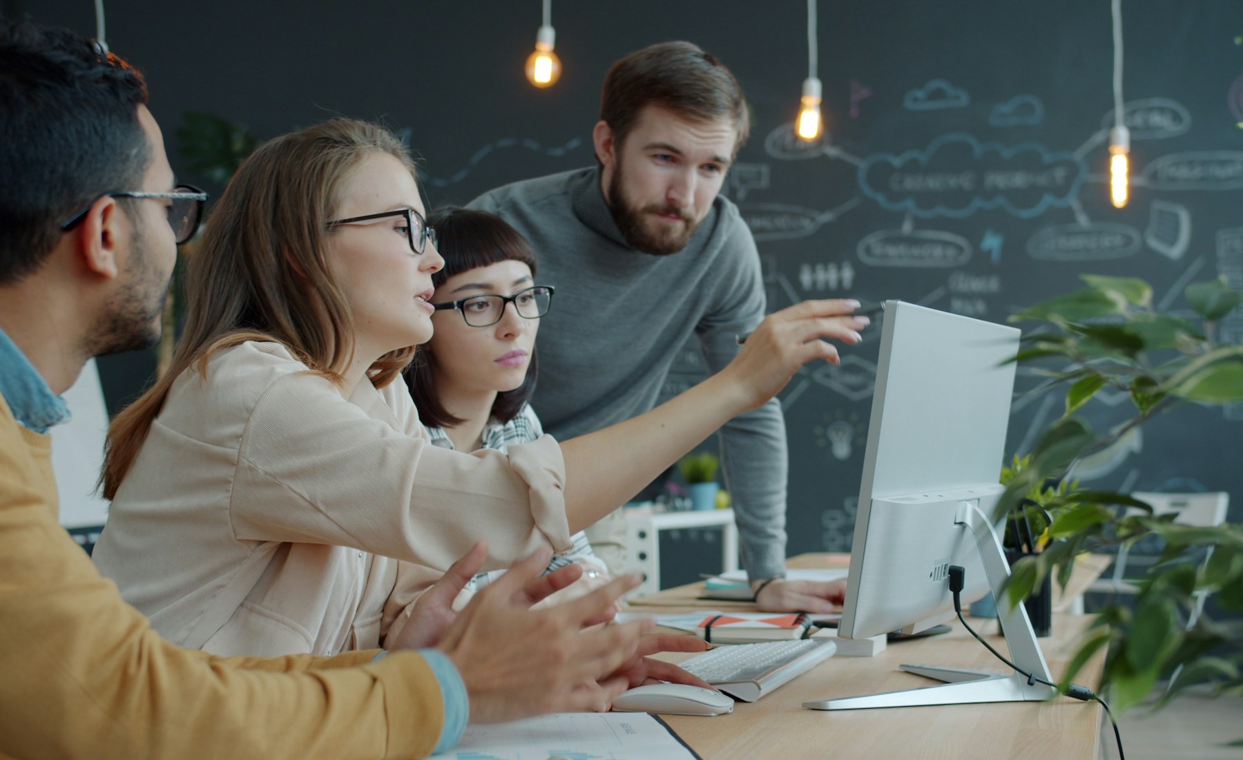 Real estate team collaborating around one computer in a modern office